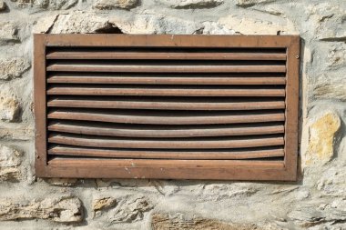 Eskimiş ahşap bir menfez. Döşemeli taş bir duvarın içine yerleştirilmiş, yıpranmış detaylar ve kırsal cazibe gösteren..