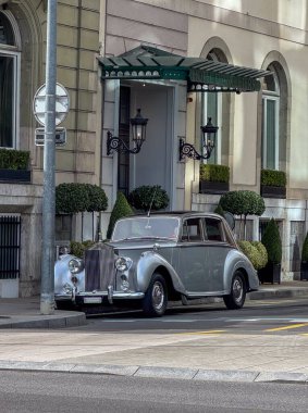 Klasik bir Rolls-Royce lüks bir otelin önüne park etmiş. Zarif ve zamansız bir entelektüellik ve tarihi bir mimari arkaplan..