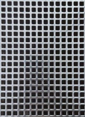 Metalik bir levhadaki kare deliklerin simetrik ızgarası, güçlü geometrik yineleme ve derinlikle modern, endüstriyel bir doku yaratıyor..