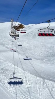 Başkanlıklar, dağdaki kayakçıları taşıyan açık mavi gökyüzünün altında, karlı dağların üzerinde süzülüyorlar..