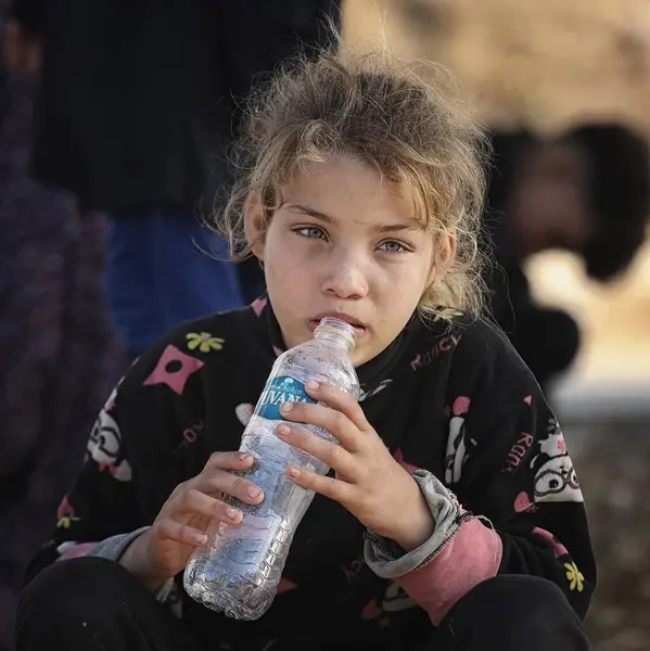 Küçük bir Filistinli kız elinde boş bir şişe tutuyor ve GAZA şeridindeki kıtlığı ve su sıkıntısını gösteriyor. Su kıtlığı konsepti. Gazze çocukları akut su kriziyle karşı karşıya. Üzüntü. Savaş konsepti. İsrail Hamas savaşı