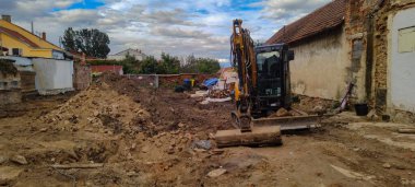 Sonbaharda Çek Cumhuriyeti 'nde bir yerleşim yerinin inşaatı askıya alınmış. Yıkılmış bir ev, vakıf için çukur kazan bir traktör.