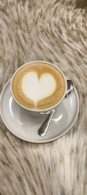 Coffee with milk foam in the shape of a heart, on a gray background in a cafe. High quality photo clipart