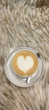 Cappuccino in a white cup on a speckled table, in a white saucer with a spoon. High quality photo clipart