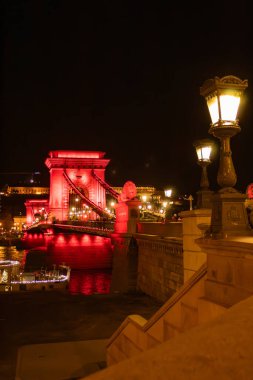 Antique lanterns against the background of the Chain Bridge with red illumination, at night in Hungary, Budapest. High quality photo clipart