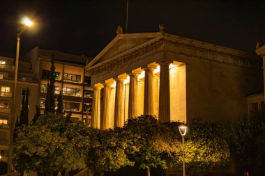 Aydınlatılmış sütunları olan mimari bina, portakal ağaçları yakınında, akşam Atina, Yunanistan. Yüksek kalite fotoğraf