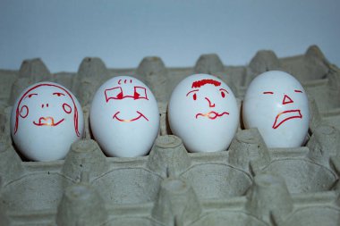 Karton bir tepside beyaz arka planda ilginç yüzlü beyaz yumurtalar. Yüksek kalite fotoğraf