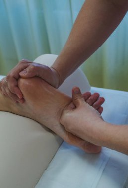 Bir masörün elleriyle, bir masaj yastığının üzerinde, arka planda, dikey bir fotoğrafta, kadın ayaklarına masaj yapma süreci. Yüksek kalite fotoğraf