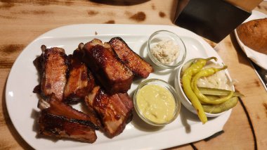 Beyaz bir tabakta füme domuz kaburgası hardallı ve turşulu, ahşap bir masada turşu. Yüksek kalite fotoğraf