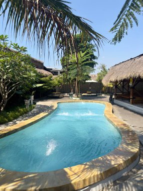 Palmiye ağaçları ve çatılı tropik bir tatil köyü.