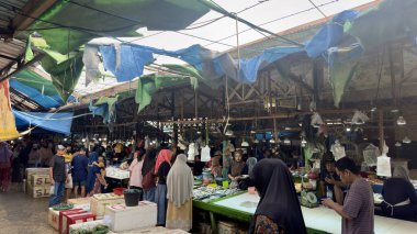 Endonezya 'nın hareketli balık pazarı. Çatı brandası parçalanmış. Satıcılar ve müşteriler taze deniz ürünleri seçiyor..