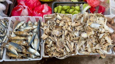 Bir market tezgahında beyaz plastik kasalarda üç çeşit kurutulmuş balık bulunur. Bir sandıkta koca bir balık, diğerinde kurutulmuş balık, üçüncüde ise küçük kurutulmuş balık var..