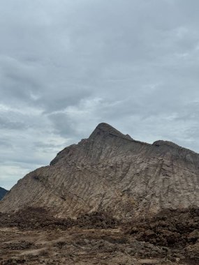 Bulutlu gökyüzü altındaki dramatik dağ manzarası seyahat broşürleri ve yayınları için güçlü bir görsel sunuyor. Engebeli dokusu bir ölçek ve saygı hissi veriyor..