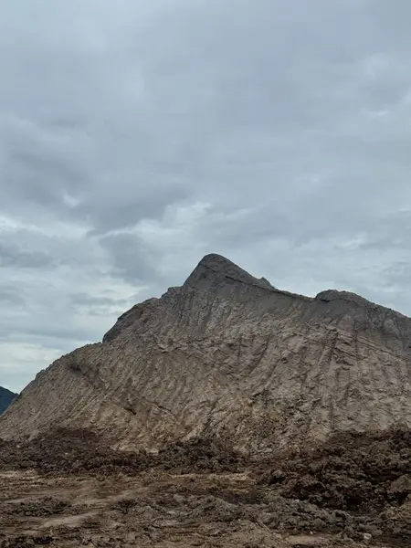 Bulutlu gökyüzü altındaki dramatik dağ manzarası seyahat broşürleri ve yayınları için güçlü bir görsel sunuyor. Engebeli dokusu bir ölçek ve saygı hissi veriyor..