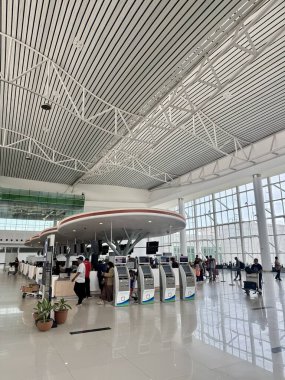 Yolcular, parlak bir havaalanı terminalindeki modern self-servis kayıt gişelerinde bekliyorlar. Geniş salonda yüksek bir tavan ve büyük pencereler bulunur. Seyahat teknolojisi kusursuz yolculuk.