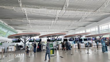 Yolcular uçuş detaylarını gösteren büyük ekranların yer aldığı modern havaalanı büfelerinde rahatça bekliyorlar. Geniş, parlak terminal kusursuz bir seyahat deneyimi sunuyor. Havaalanı iç tasarımı.