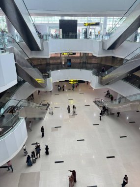 İçinde yürüyen merdivenler ve açık bir alan bulunan çağdaş bir havaalanı terminalinin yüksek açılı görüntüsü..
