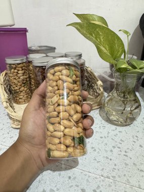 Yeşillik ve diğer konteynırlarda sergilenen açık bir kavanozdaki lezzetli kavrulmuş fıstık atıştırmalıkları çeşitli kıtır kıtır yiyecekleri sergiliyor..