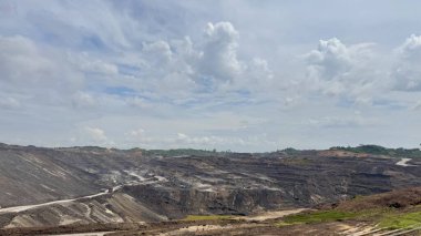 Kısmen Bulutlu Gökyüzü altındaki Geniş Taş Devri Manzarası dramatik toprak çalışmalarını ve madencilik operasyonlarını gösteriyor.