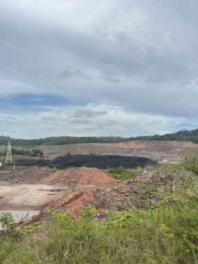 Uçsuz bucaksız açık kömür madenleri üzerinde dramatik bulutlu gökyüzü kazılmış toprak ve karanlık madde yığınlarını gösteriyor..