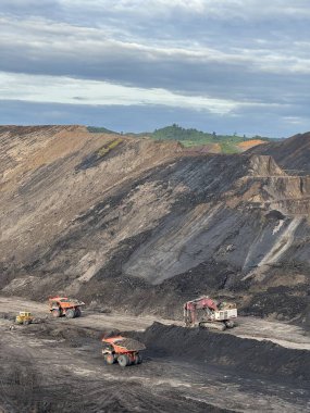 Bulutlu Gökyüzü Altında Açık Kömür Madenciliği Operasyonu Ağır Makineleri ve Kazılmış Dünya 'yı Gösteriyor