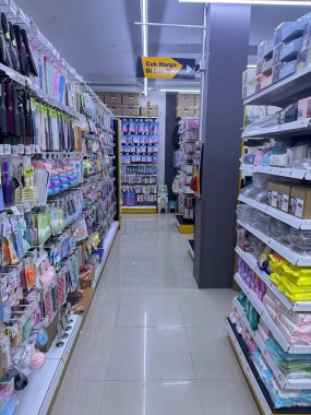 Parlak perakende mağazası koridorunda renkli ev eşyaları ve güzellik ürünleri raflarda düzgünce sergileniyor