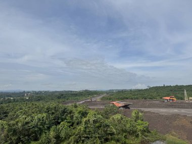 Bulutlu Bir Gökyüzü Altında Yeşillik Yol ve İnşaat 'ın bir ipucuyla Serene Manzarası. Kömür Madenciliği Açık Çukur