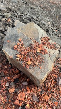 Kırık kırmızı tuğlaların, molozların, endüstriyel enkazların, döküntü dokuların arasında büyük gri bir taş duruyor.