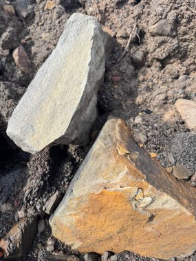 Koyu toprak arka planda dinlenen kaba yontulmuş taşlar Doğal Kaya Dokuları Toprak Tonolojisi