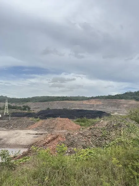 Uçsuz bucaksız açık kömür madenleri üzerinde dramatik bulutlu gökyüzü kazılmış toprak ve karanlık madde yığınlarını gösteriyor..