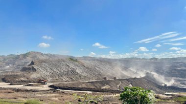Parlak mavi gökyüzü altında ağır makineler ve ekipmanlarla maden işletmesi, endüstri sahnesi