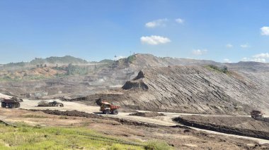 Büyük kamyonlar ve makineler açık kömür madeninde çalışıyor açık mavi gökyüzünün altında, endüstri