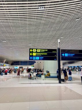 Gezginler modern havaalanı terminalinde dolaşır, varış noktalarını arar, uçuşun heyecanını hissederler.