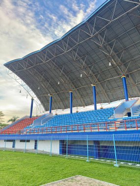 Modern bir stadyum heyecan verici sporlar için mükemmel bir zemin sunar. Renkli oturma yerleri ve yemyeşil alanlar canlı bir atmosfer yaratıyor. Etkinlikleri, seyahatleri veya sporla ilgili işleri desteklemek için ideal.