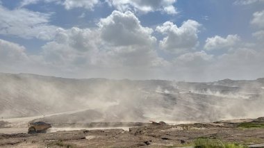 Açık kömür madenciliği faaliyetlerinin atmosferi, güneşli bir günde tozla dolu yoğun yollar.
