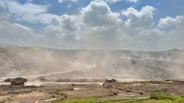 Dusty arid landscape with mountains under a cloudy sky, showcasing nature's raw power and resilience in a remote, untouched environment. activity of open pit coal mining