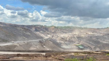 Dynamic aerial view of a working quarry featuring heavy machinery and dramatic landscapes, showcasing industry and environmental impact