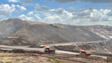 Mining operation with heavy machinery and open pit mine under dramatic sky showcases industrial power and resource extraction challenges