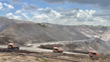 Dynamic view of heavy machinery in action at a mine site under a vibrant sky showcasing industry and environmental impact