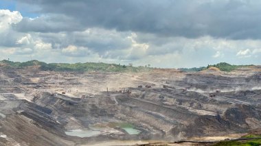 Powerful aerial view of vast open-pit coal mine landscape under cloudy skies showing industrial scale energy production and environmental impact