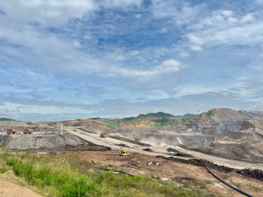 Açık çukur madenciliğinin dinamik hava görüntüsü, canlı bir gökyüzüne karşı ağır sanayi görüntüsü, inşaat ve enerji projeleri için mükemmel.