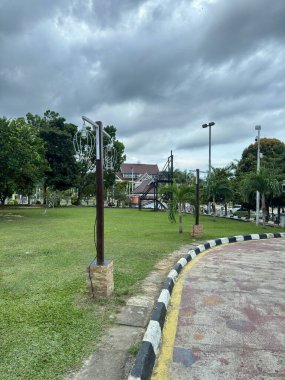 Peaceful green park with cloudy sky inviting relaxation and outdoor activities, ideal for travel and nature-themed projects, calmness