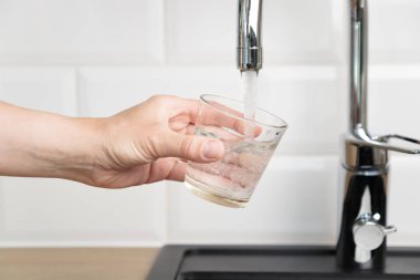 Susamış insan su içmek ve mutfak musluğundan bir bardak saf suyu beyaz kiremitlerle doldurmak istedi. Doğal suyun saflığı ve temizliği kavramı, kopyalama alanı ile pankart