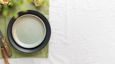 Çatal bıçaklı, beyaz masa örtüsü üzerinde boş, eski, yeşil bir tabak. Yemek tabakları için arka plan olarak kopyalama alanı, yemek modeli.