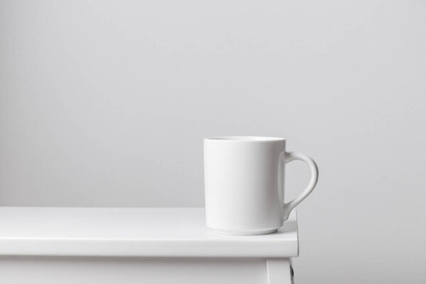 Белая керамическая кружка на краю белого деревянного стола, горизонтальный макет баннера с копировальным пространством