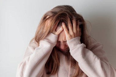 Depresyonda olan genç bir kadın migren ağrısı çekiyor. Elleri başının üstünde, yatakta yalnız başına oturuyor. Stres altında, üzgün ve endişeli. Boşluğu kopyala