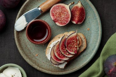 Taze incir dilimli, krem peynirli ve ballı sandviçe yakından bakın. Sağlıklı beslenme. Vejetaryen kahvaltısı, öğle yemeği veya abur cubur tarifi, sade anahtar, üst manzara, koyu arkaplan