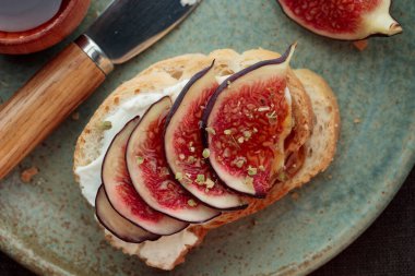 Taze incir dilimli, krem peynirli ve ballı sandviçe yakından bakın. Sağlıklı beslenme. Vejetaryen kahvaltısı, öğle yemeği veya abur cubur tarifi, sade anahtar, üst manzara, koyu arkaplan