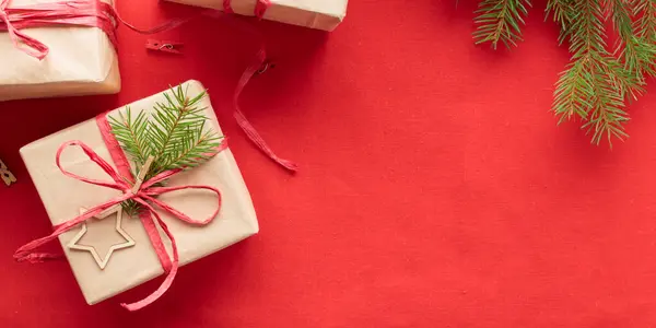 Christmas and zero waste, eco-friendly natural packaging gift boxes in craft paper on a red textile background, eco Christmas holiday concept, eco decor banner with copy space