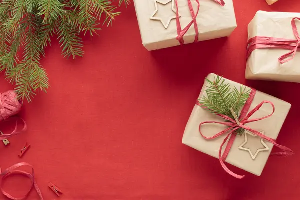 Christmas and zero waste, eco-friendly natural packaging gift boxes in craft paper on a red textile background, eco Christmas holiday concept, eco decor banner with copy space